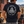 Man wearing a FreedomBuilt Don't Tread on Me navy blue graphic tee featuring a white rattlesnake and America 1776 back print, standing beside a vintage pickup truck.